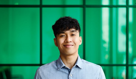 man smiling directly at camera with green background