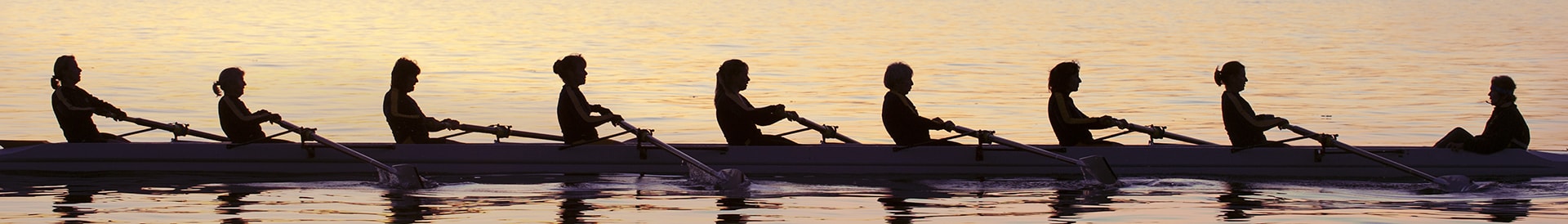 people rowing canoes in sunset